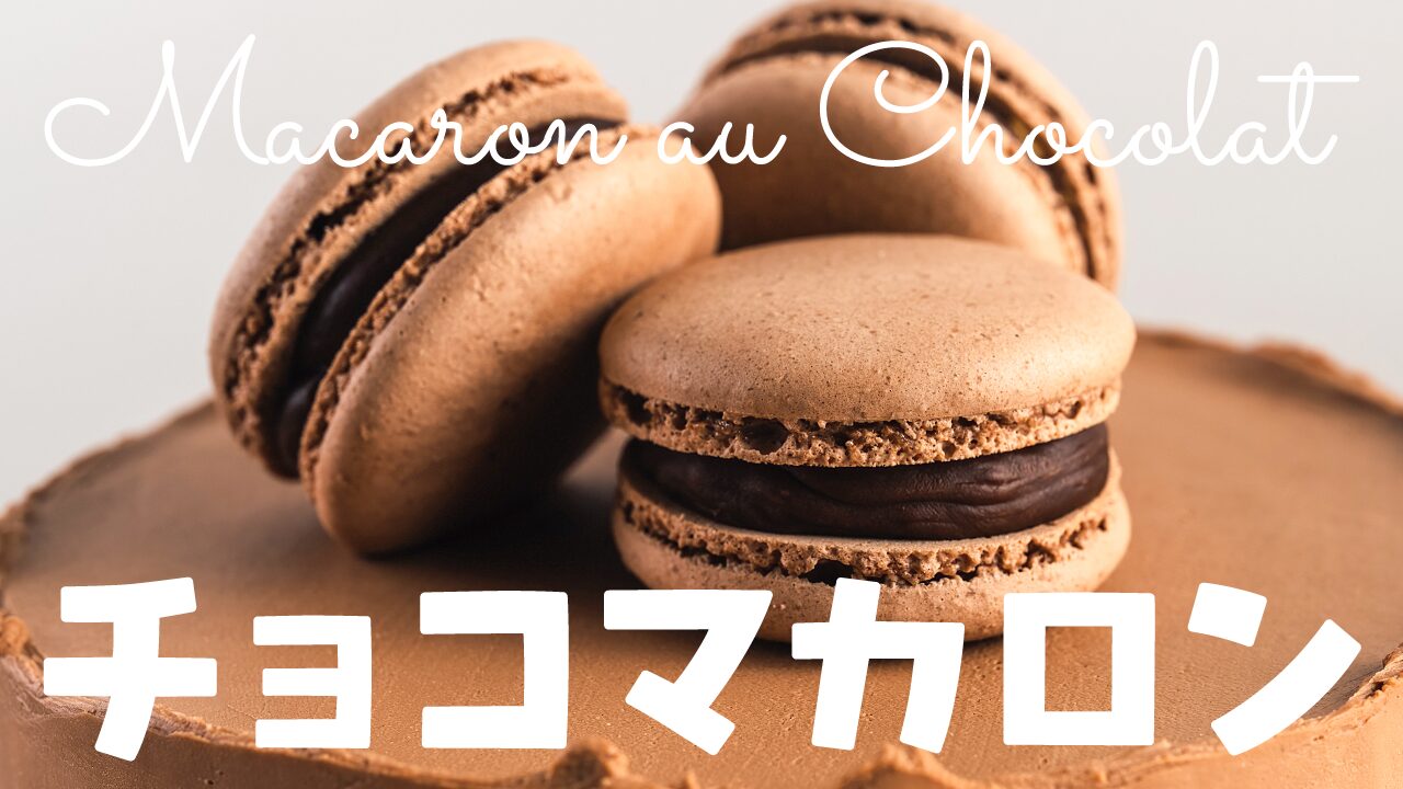チョコレートケーキの上に置かれたチョコマカロンのアップ写真に、『Macaron au Chocolat』と『チョコマカロン』という文字を重ねたお菓子作り・スイーツ系YouTubeサムネイルの作例。筆記体のフリーフォント『Sacramento』を使用しています。（バイブデザインのおもち制作）