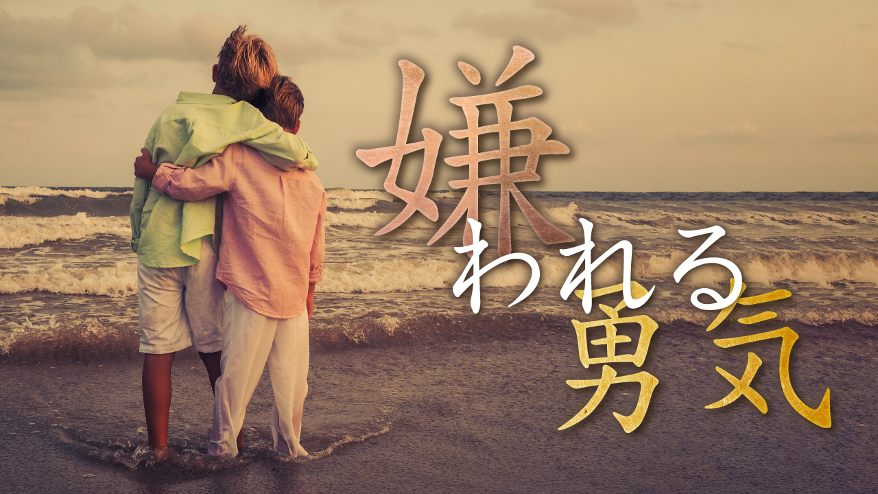 海辺で肩を組み、荒れる海を見つめる二人の少年の後ろ姿の写真に、『嫌われる勇気』という文字を重ねた自己啓発・書籍解説系YouTubeサムネイルの作例。(バイブデザインのおもち制作)